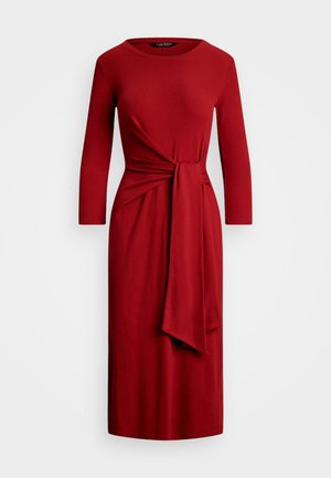Red jersey dress with long sleeves, round neckline, and a front knot detail. Falls to mid-calf, featuring a smooth texture and fitted silhouette.