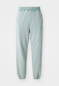 Lysgrønne sweatpants lavet af blød bomuld, med elastisk talje, sidelommer og diskret grafisk detaljering langs det ene ben.