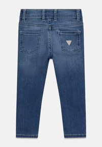 Dark blue denim jeans with a slim fit, featuring two back pockets and a small triangular logo in a lighter shade.