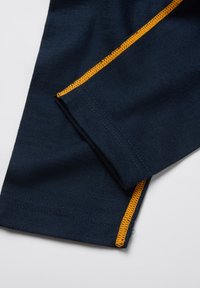 Marine stof met oranje stiksels, met een gladde textuur. Toont een close-up van de zoom van een mouw, waarbij de contrasterende stiksels en strakke lijnen zichtbaar zijn.