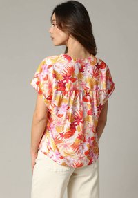 Bloemige blouse met korte mouwen, gekenmerkt door een roze, gele en rode print, een geplooid detail aan de achterkant en een lichtgewicht, gestructureerde stof.