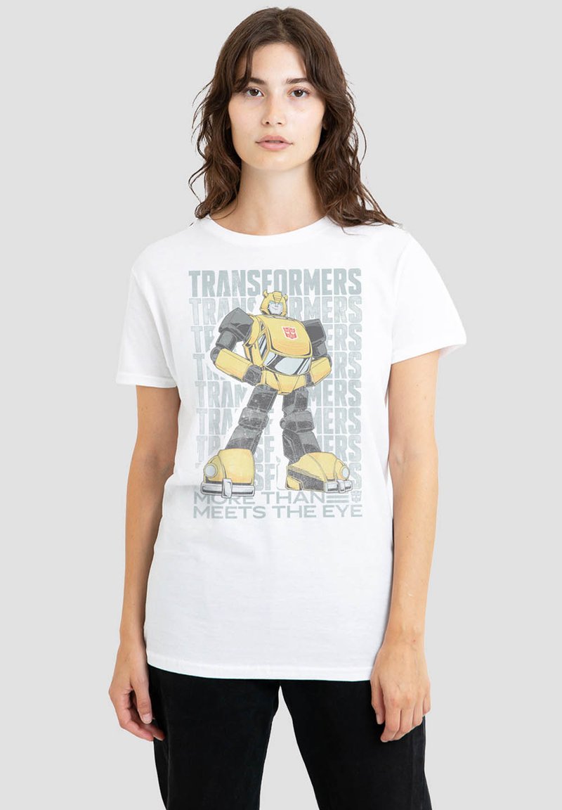 White cotton t-shirt featuring a graphic of a yellow robot with black accents, accompanied by "Transformers" text and "More Than Meets the Eye."