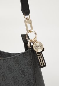 Black leather handbag featuring a textured finish, gold-tone hardware, and brand tags with embossed details. Adjustable strap included.