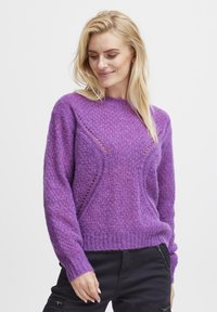 Pull en tricot violet avec une finition texturée, présentant un col rond et des découpes subtils le long des épaules et des côtés.
