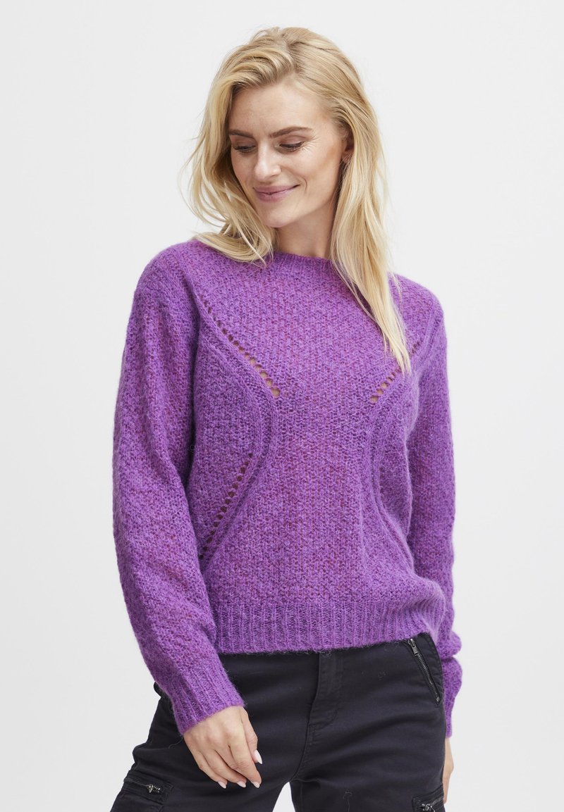Pull en tricot violet avec une finition texturée, présentant un col rond et des découpes subtils le long des épaules et des côtés.