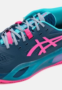 Scarpa da corsa Asics con una parte superiore blu scuro, accenti rosa, lacci grigi e un'intersuola color turchese. Presenta dettagli in mesh e un design testurizzato.