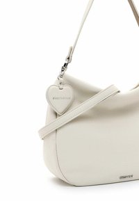 Weißes Leder-Crossbody-Bag mit einer geschwungenen Form, strukturiertem Oberflächen, abnehmbarem herzförmigen Anhänger und silbernen Hardware-Details.