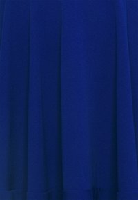 Blå klädfiber med en mjuk textur, prydd med plisseringar som skapar volym. Nyansen är livfull och djup, utan mönster eller dekorationer.