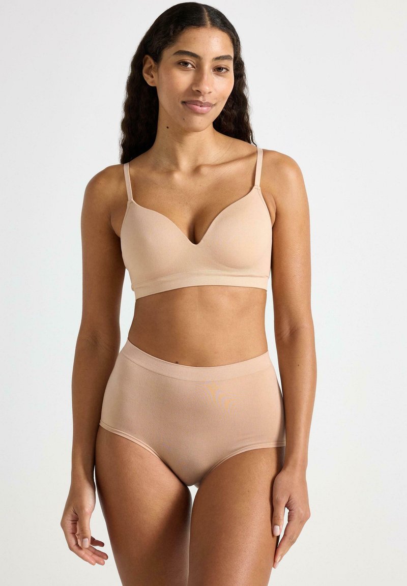 Beige draadloze beha met een diepe V-halslijn en verstelbare bandjes, gecombineerd met hoge taillebriefs, beide gemaakt van gladde stretchstof.