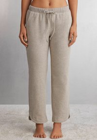Grau, weiche Lounge-Hose aus Stoff mit elastischem Bund, Kordelzugverschluss und seitlichen Schlitzen am Saum. Keine sichtbaren Taschen.