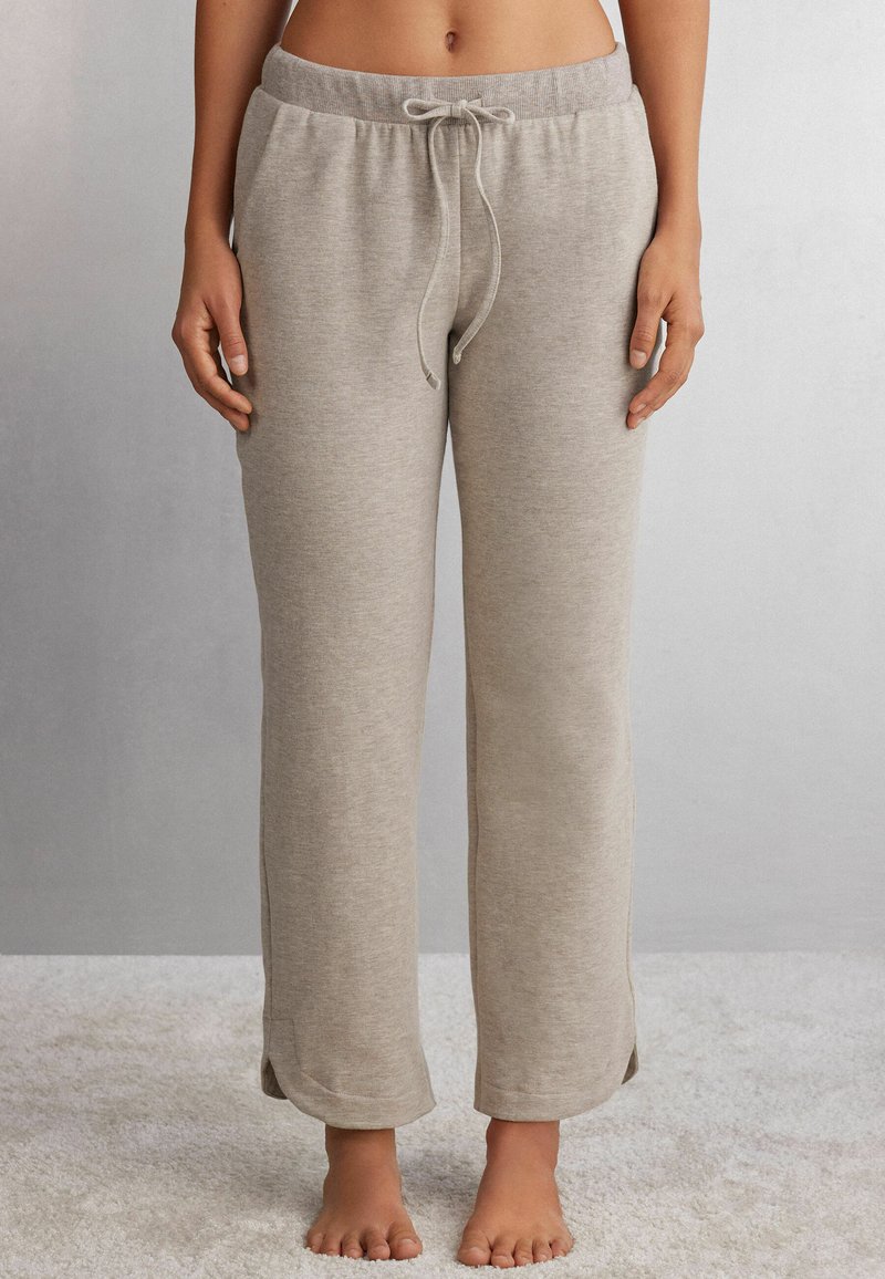 Grau, weiche Lounge-Hose aus Stoff mit elastischem Bund, Kordelzugverschluss und seitlichen Schlitzen am Saum. Keine sichtbaren Taschen.