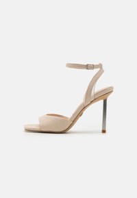 Beige korkokengät, joissa on teksturoitu käärmeennahkakuosi, avonainen varvas, kapea nilkkahihna ja metallinhohtoinen hopeinen stiletto-korko.