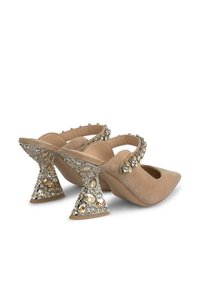Tacones de ante beige con punta afilada, que presentan una correa decorativa y un tacón de brillo embellecido con una forma única.