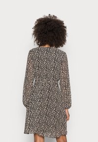 Robe noire à manches longues, ornée d'un motif abstrait beige clair. Tissu léger avec une taille cintrée et une jupe évasée.