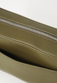 Olive green leather pouch with silver zipper. Smooth texture with clean lines and a single interior compartment, no visible patterns.