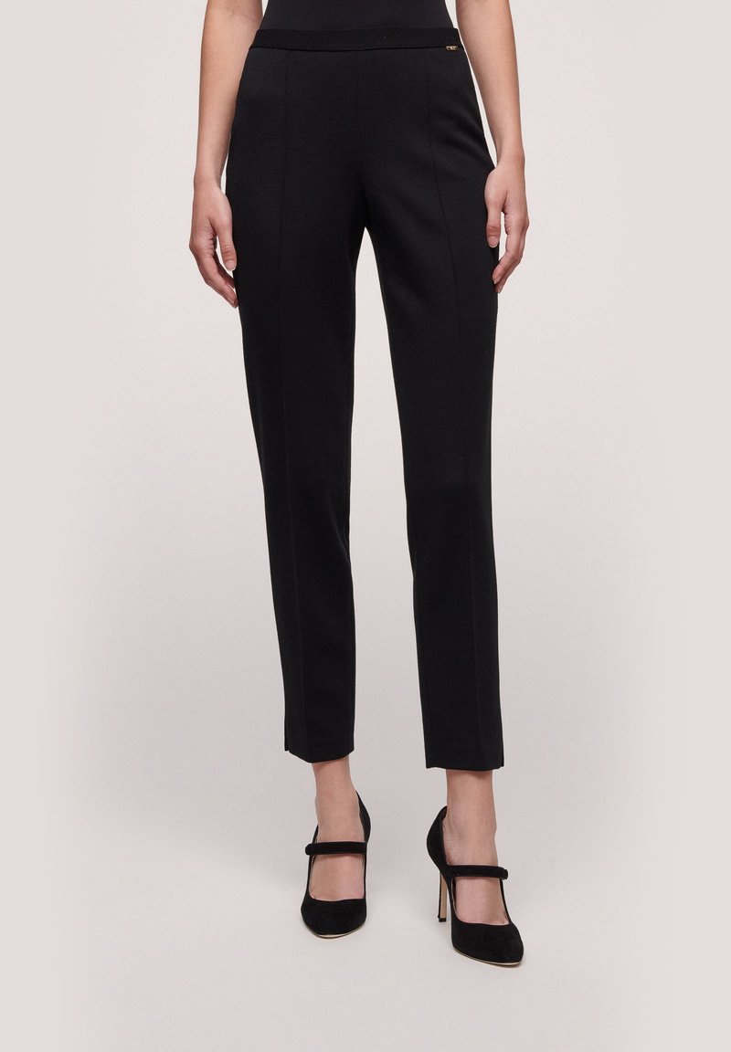 Pantaloni neri su misura realizzati in un tessuto elegante, con una vita decorata da un discreto accento dorato. Vestibilità slim con lunghezza cropped.