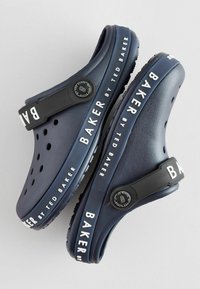 Marineblå klip klapper med sort rem og hvid skrift "BAKER by TED BAKER." Har huller til ventilation og et rundt design.