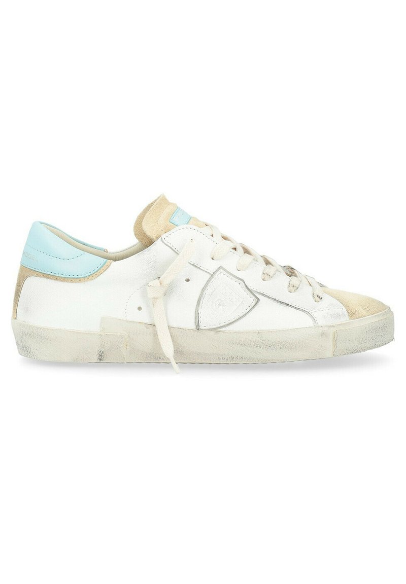 Sneaker bianca in pelle con accenti blu e beige, caratterizzata da una suola in gomma testurizzata, design classico con lacci e un lieve dettaglio del logo.