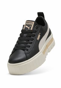 Sneaker in pelle nera con accentuazione in suede bianco, suola platform spessa color crema, lacci neri e logo sulla linguetta. Design minimalista.