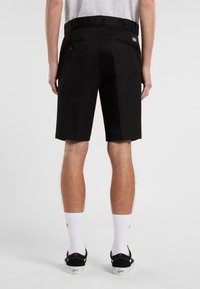 Black fabric shorts with a straight cut, featuring side and back pockets, a waistband with belt loops, and visible stitching details.