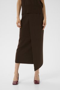 Brown woolen skirt with a wrap design, featuring a straight shape and knee-length cut. The model wears burgundy high-heeled shoes.