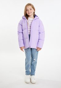Giacca puffa lavanda con cappuccio, chiusura con zip e una texture liscia; indossata sopra una camicia a righe e abbinata a jeans azzurri e sneakers bianche.