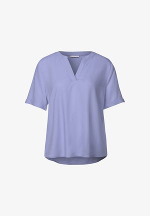 Blusa lilla a maniche corte con scollatura a V, caratterizzata da una vestibilità ampia e una texture di tessuto liscia. L'orlo è leggermente curvo sul retro.