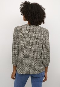 Sort og creme farvet bluse med mønster, løs pasform, trekvartærmer og rund halsudskæring, der har geometriske designs og blødt stof.