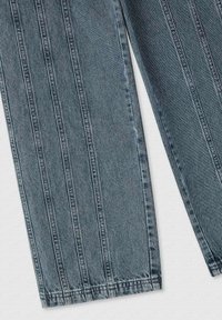 Jeans in denim indaco scuro con taglio dritto, caratterizzati da dettagli a cucitura verticale, senza tasche visibili e una finitura del tessuto leggermente testurizzata.