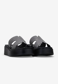 Sandalias de slide grises con un diseño de tiras texturizadas, que cuentan con recortes y una suela de plataforma negra gruesa para mayor altura.