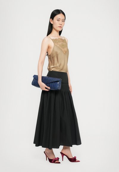 Satin top with lace detail, black pleated skirt, blue textured clutch, and red velvet high-heeled shoes with bow accents.