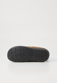 Bruine textielschoenen met een gestructureerde zwarte rubberen zool. De zool heeft een robuust profiel voor grip.