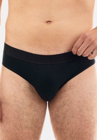 Schwarze Herrenunterhosen mit einem einfarbigen Design und einem weichen Elastikbund mit eingeprägtem Branding. Das Material sorgt für Dehnbarkeit und Komfort.