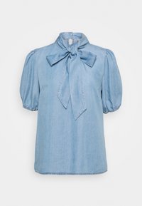 Ljusblå denimblus med rosettknut vid kragen, kort puffärm och rak skärning. Mjuk textur med diskret glans.