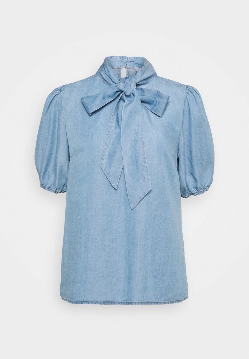 Ljusblå denimblus med rosettknut vid kragen, kort puffärm och rak skärning. Mjuk textur med diskret glans.