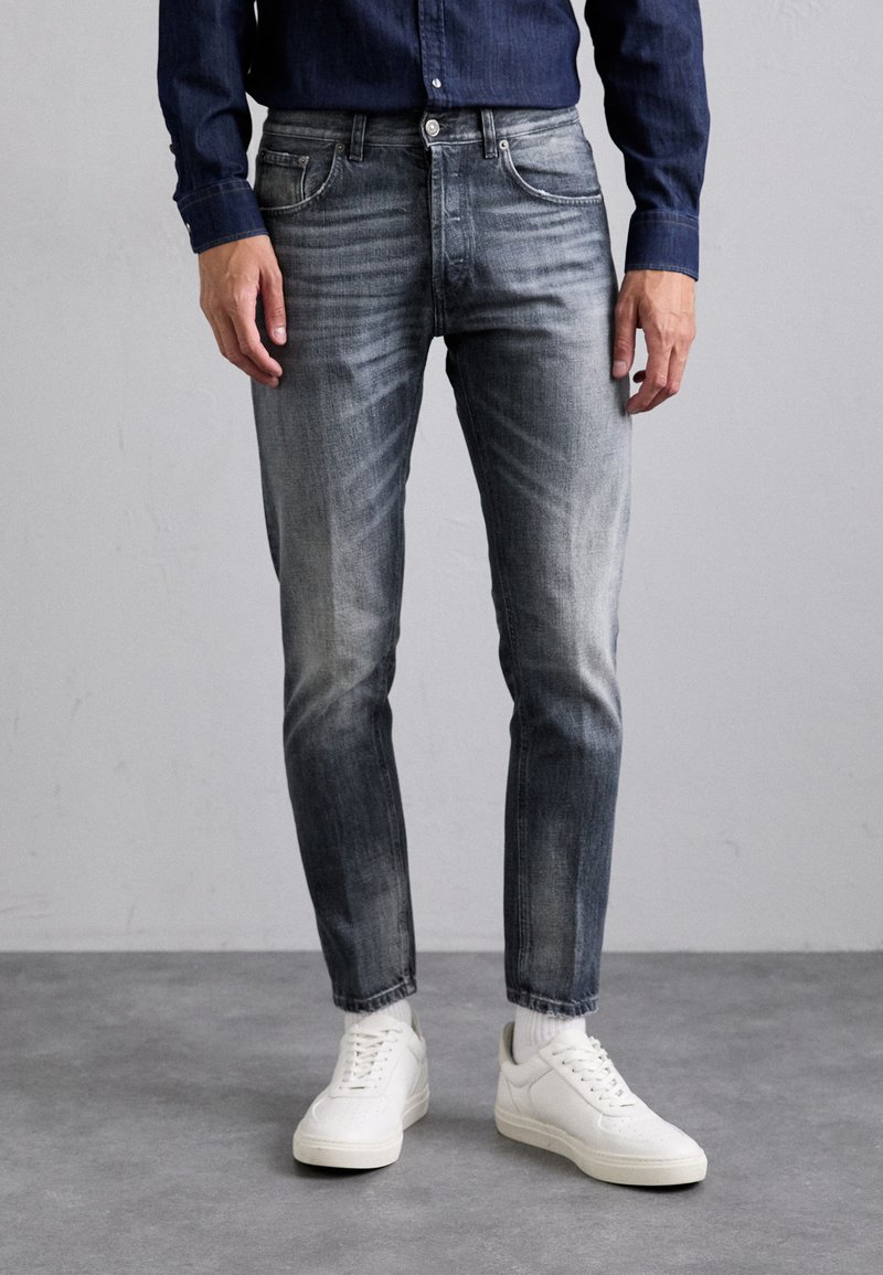 Jeans skinny, grigio sbiadito, con un classico design a cinque tasche. Abbinati a sneaker bianche. Il tessuto presenta sottili variazioni di lavaggio e texture.