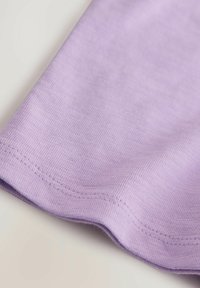 Fliederfarbenes Stoffmaterial mit glatter Textur, das einen leicht geschwungenen Saum und feine Nähte entlang der Kanten aufweist.