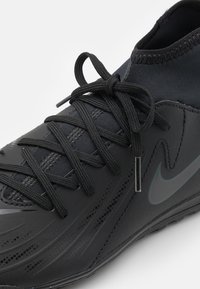 Black athletic shoe featuring a smooth synthetic upper, textured design, flat laces, and a subtle logo detail on the side.