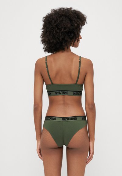 Olive zelena kompleta spodnjega perila z krojenim modrcem in ujemajočimi se hlačkami. Vključuje črno blagovno znamko "MOSCHINO" na elastičnih trakih. Preprost dizajn.