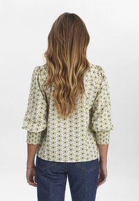 Blusa a fiori in verde chiaro e bianco, con maniche a palloncino, polsini smock e orlo arrotondato. Progettata con motivi floreali ripetuti.