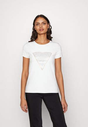 T-shirt bianco a maniche corte con un logo "GUESS" triangolare glitterato centrato sul petto, realizzato in cotone con una texture morbida.
