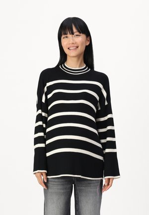 Black and white striped knit sweater with a high neckline and long sleeves, featuring a ribbed texture and relaxed fit.