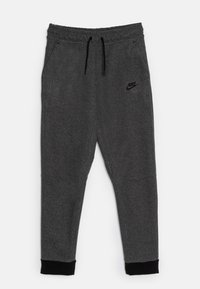 Pantalons de jogging Nike gris avec une taille à cordon, poches latérales et poignets noirs. Présente un logo en relief discret sur la cuisse gauche. Texture douce.