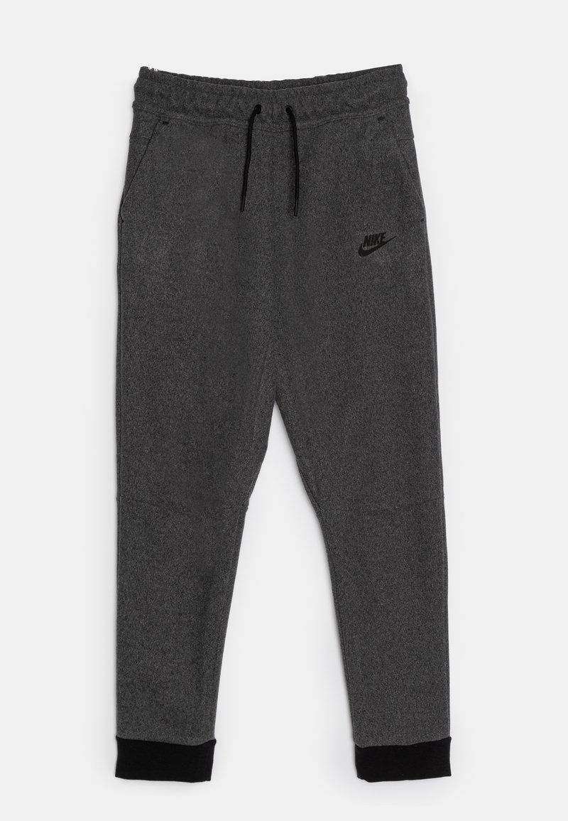 Pantalons de jogging Nike gris avec une taille à cordon, poches latérales et poignets noirs. Présente un logo en relief discret sur la cuisse gauche. Texture douce.