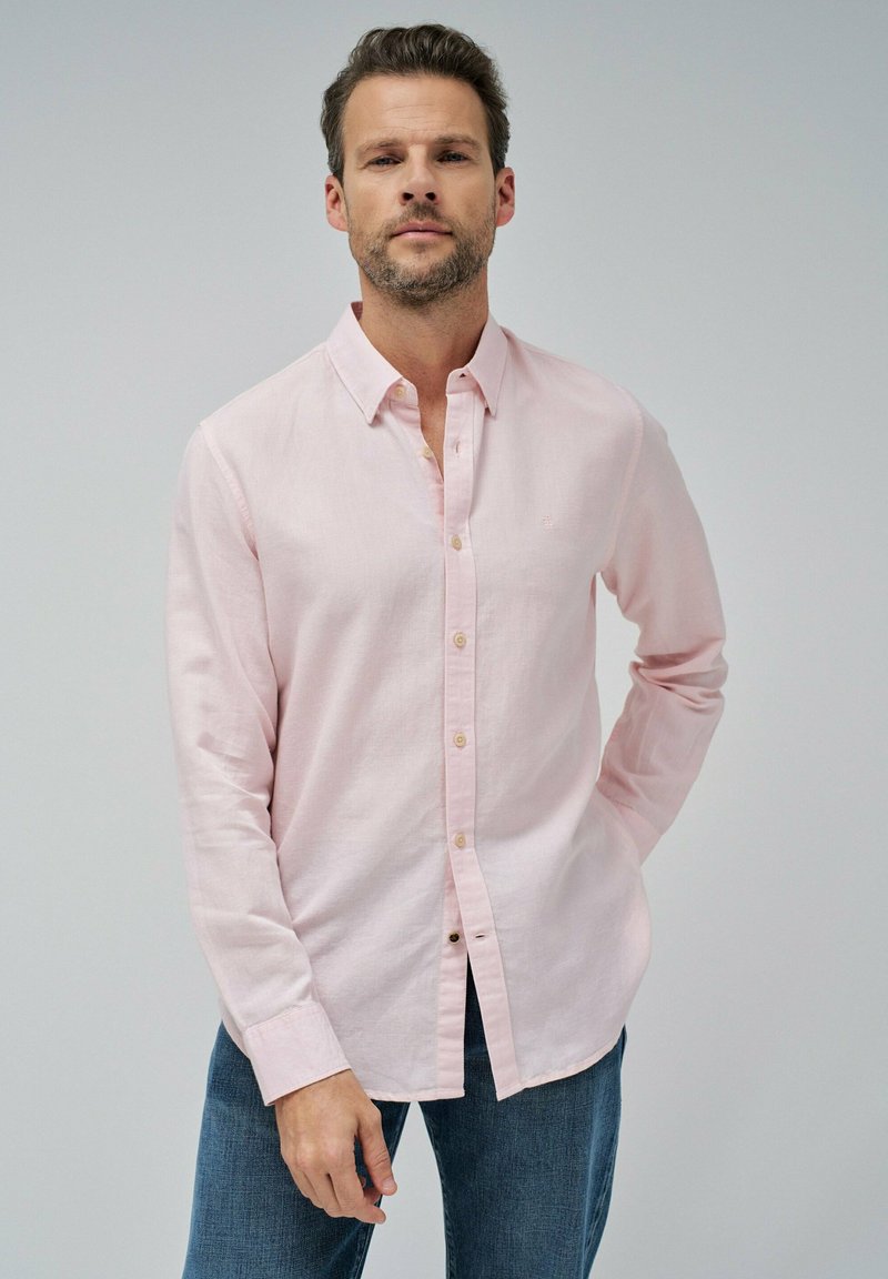 Camisa de botones rosa claro con mangas largas, hecha de una mezcla de lino, que presenta un cuello clásico y detalles de costura sutiles, combinada con jeans azules.
