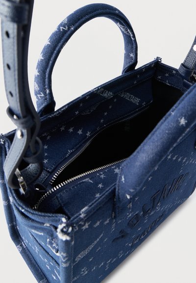 Τσάντα ώμου από μπλε ύφασμα με σχέδια αστεριών, επάνω μέρος με φερμουάρ ανοιχτό και δύο χερούλια, που δείχνει το εσωτερικό και μέρος του ρυθμιζόμενου ιμάντα ώμου.