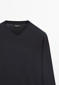 Dunkelblaues V-Ausschnitt-Pullover aus einem glatten Strickstoff. Mit einem gerippten Kragen und Bündchen, sowie einem Etikett, das die Marke und das Herstellungsland angibt.