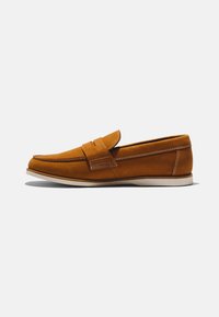 Mocassin marron en cuir à enfiler avec semelle blanche et coutures blanches visibles sur fond blanc, présenté de profil.