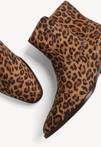 Stivaletti alla caviglia con stampa leopardata, superficie morbida e strutturata, punta affusolata e tacco basso a cubetto. Schema di colori marrone, nero e beige.