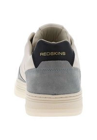 Heren sneaker met een beige leren bovenkant, grijze suède accenten, blauwe details en een witte rubberen zool. "REDSKINS" logo in goud op de hak.